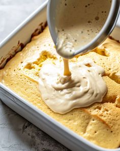 a person pouring sauce on top of some food in a white dish with a spoon