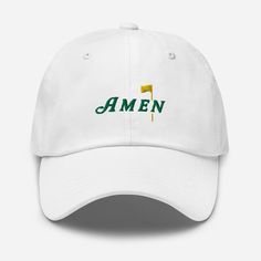 Capture the essence of Augusta with our exclusive Masters-inspired hat. Crafted with meticulous detail, it showcases intricate embroidery of the revered AMEN phrase, echoing the spirit of tradition and excellence synonymous with the prestigious tournament. Whether you're on the course or cheering from the sidelines, this hat is a must-have for every golf aficionado's collection. * 100% chino cotton twill * Green Camo color is 35% chino cotton twill, 65% polyester * Unstructured, 6-panel, low-profile * 6 embroidered eyelets * 3 ⅛" (7.6 cm) crown * Adjustable strap with antique buckle * Blank product sourced from Vietnam or Bangladesh This product is made especially for you as soon as you place an order, which is why it takes us a bit longer to deliver it to you. Making products on demand in Golf Hats, Camo Colors, The Masters, Intricate Embroidery, Green Camo, Trucker Cap, Cotton Twill, Low Profile, Baseball Cap