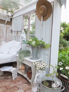 a bed sitting next to a window in a room filled with plants and potted plants