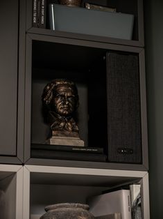 a busturine is placed in the corner of a bookcase