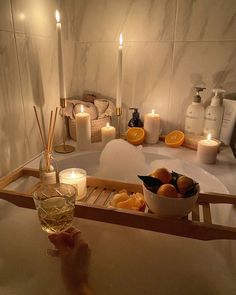 a person holding a wine glass in front of a tray with oranges and candles