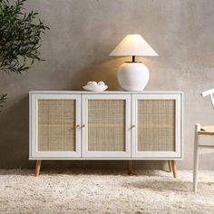 a white cabinet with wicker doors and a lamp next to it on a carpeted floor