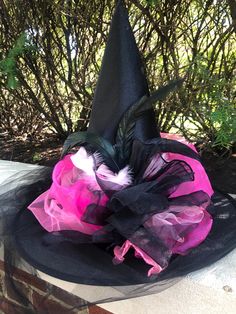 Beautiful witch hat has a very elegant Parisian style with various pinks and black tulle and organza all around. Long black tulle train cascades in the back to finish this unique hat.  One size fits most head circumferences up to 23 inches.  Other colors are possible. Please inquire for more information. Witchy Fitted Party Hat, Fitted Witchy Party Hat, Pink Halloween Costume Hats And Headpieces, Pink Costume Hats And Headpieces For Halloween, Whimsical Black Hats For Themed Events, Whimsical Black Hat For Themed Events, Pink Halloween Costume Hat, Whimsical Black Costume Hats And Headpieces For Parties, Pink Witch Hat