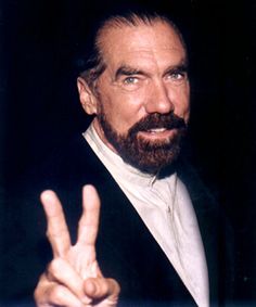 a man with a goatee and beard making the peace sign in front of him