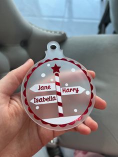 a person holding up a glass ornament with the name jane and harry on it