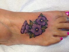 a woman's foot with purple flowers on it