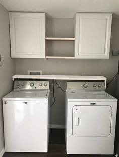 two washers and a dryer in a small room with white cabinets on the wall