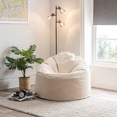 a white bean bag chair sitting on top of a wooden floor next to a potted plant