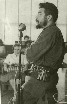 an old photo of a man holding a microphone in front of other men sitting down