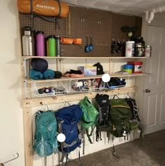 there are many backpacks hanging up on the wall in this small room with shelves