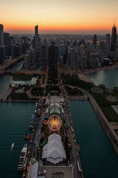 an aerial view of the city skyline at sunset with ferris wheel and water in foreground