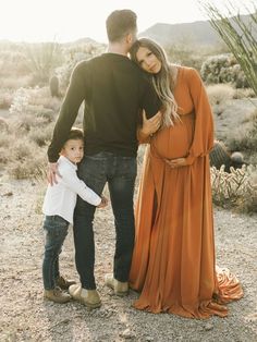 a man and woman standing next to a child in the desert