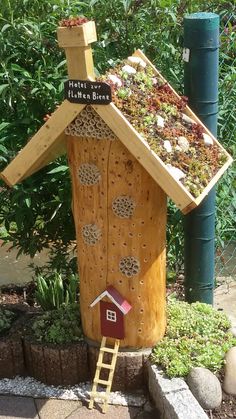 a bird house made out of wood with plants growing on it and a ladder leading up to the roof