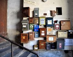 there are many mail boxes on the wall next to each other in front of some stairs