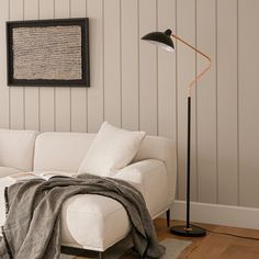 a living room with a white couch and black floor lamp