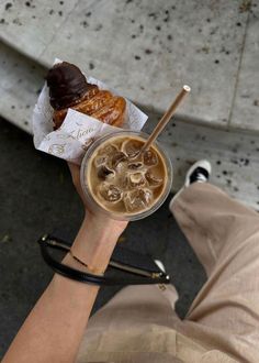 a person holding up a cup of coffee and pastries