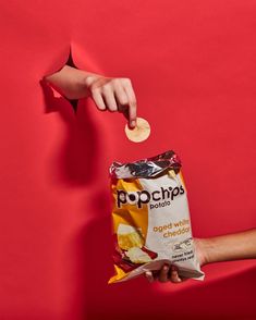 a person holding a bag of chips in their right hand and reaching for it with the other hand