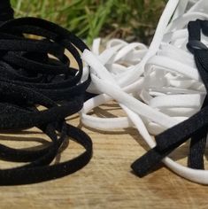 white and black rubber bands are on a wooden surface with grass in the back ground