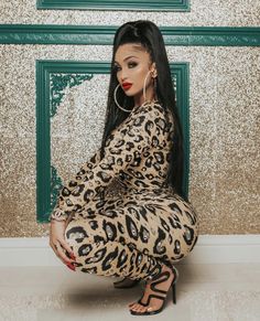 a woman sitting on the ground in leopard print pants and heels with her legs crossed