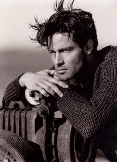 black and white photograph of a man leaning on a fire hydrant with his hand on his chin