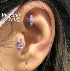 a close up of a person's ear with some piercings on top of it