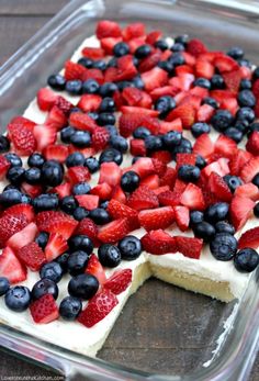 a cake with strawberries and blueberries on top in a glass dish, ready to be eaten