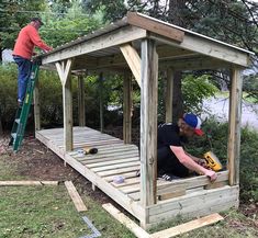 two men working on a wooden structure in the woods