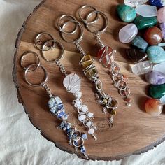 several different types of jewelry are on a wooden tray next to beads and stones,