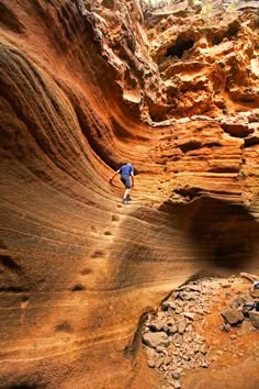 a man climbing up the side of a cliff in an area that looks like a canyon