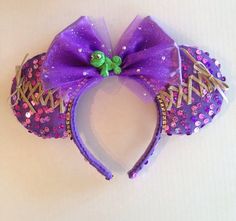 a purple minnie mouse headband with a green frog on it's side and sequins around the ears