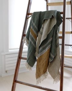 a blanket is hanging on a ladder next to a window