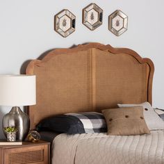 the headboard of a bed is made with wicker and has three mirrors above it