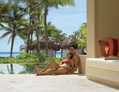 a man and woman sitting next to each other in front of a pool with palm trees