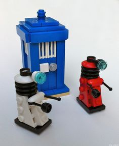 two legos are sitting next to each other on a table, one has a blue phone booth and the other is red