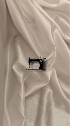 an old sewing machine sitting on top of a white sheet covered in satin material,