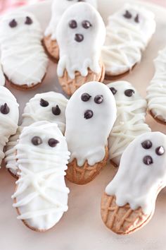 some cupcakes with white icing and chocolate chips on them are decorated like ghost faces