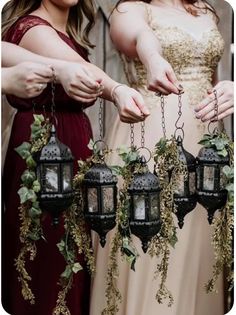 three bridesmaids holding lanterns with greenery hanging from them