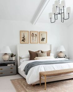 a bedroom with a bed, dressers and two lamps hanging from the ceiling above it