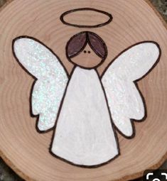 an angel painted on a piece of wood sitting on top of a wooden slice with glitters