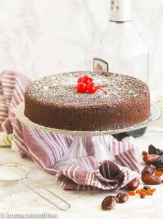 a chocolate cake sitting on top of a glass plate next to a bottle of wine