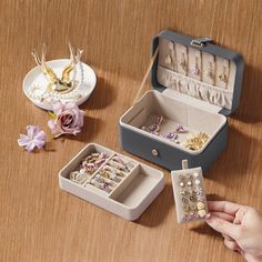 an open jewelry box sitting on top of a wooden table next to other jewelry boxes