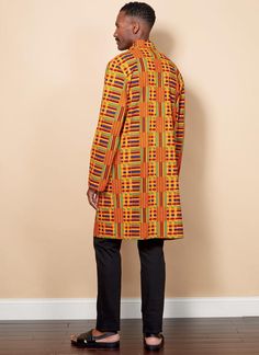 a man standing in front of a wall wearing an african print coat