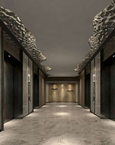 an empty hallway with several doors and lights on either side of the corridor is lit by recessed lighting