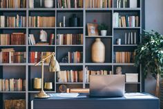 a laptop computer sitting on top of a desk in front of a bookshelf