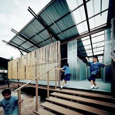 two children are climbing up the stairs in front of a building with metal slats