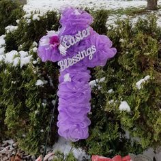 there is a purple teddy bear in the snow next to some bushes and trees with words written on it