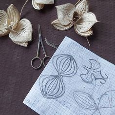 some flowers and scissors are laying on a sheet of paper with crochet work