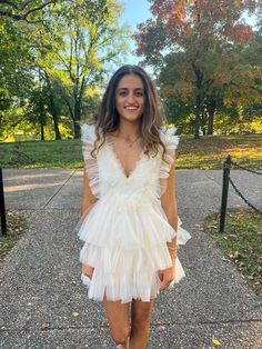 a woman in a short white dress posing for the camera