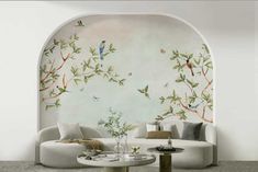 the living room is decorated in white and has birds painted on the wall above the couches