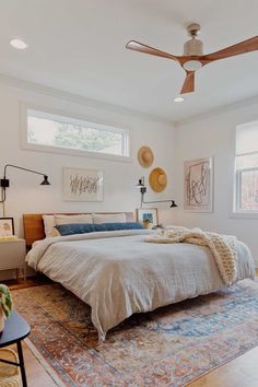 a bedroom with a bed, rug and ceiling fan in the middle of the room